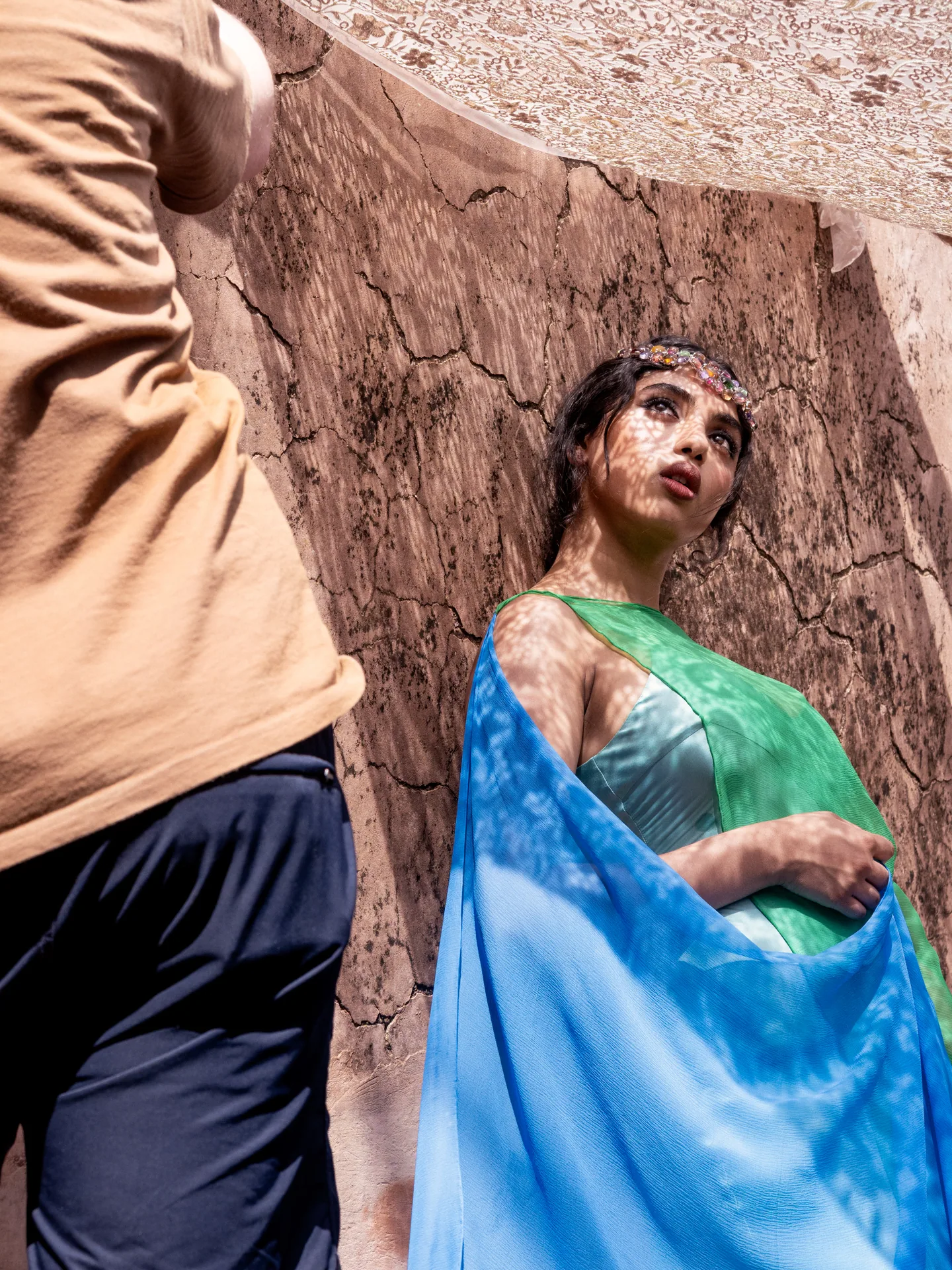 Model in gr&uuml;n-blauem Tuch vor einer Lehmwand in Rajasthan