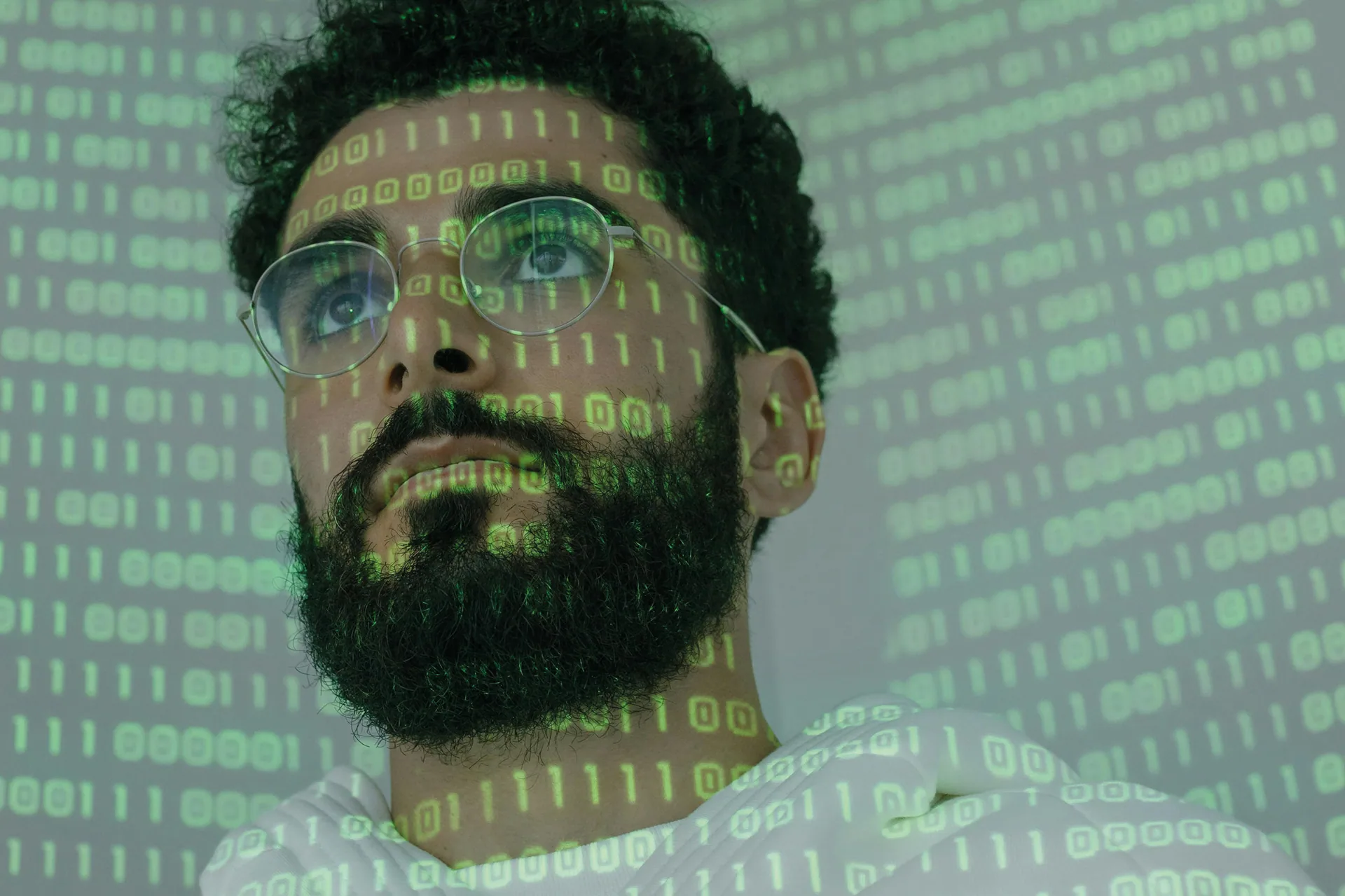 Mann mit Brille, auf dessen Gesicht Binärcode projiziert wird